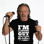 Man in black t-shirt with "I'M A SOUND GUY DON'T PUSH MY BUTTONS!" text holding microphones.